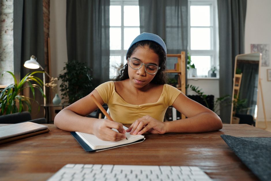 Student writing in a notebook at a study desk